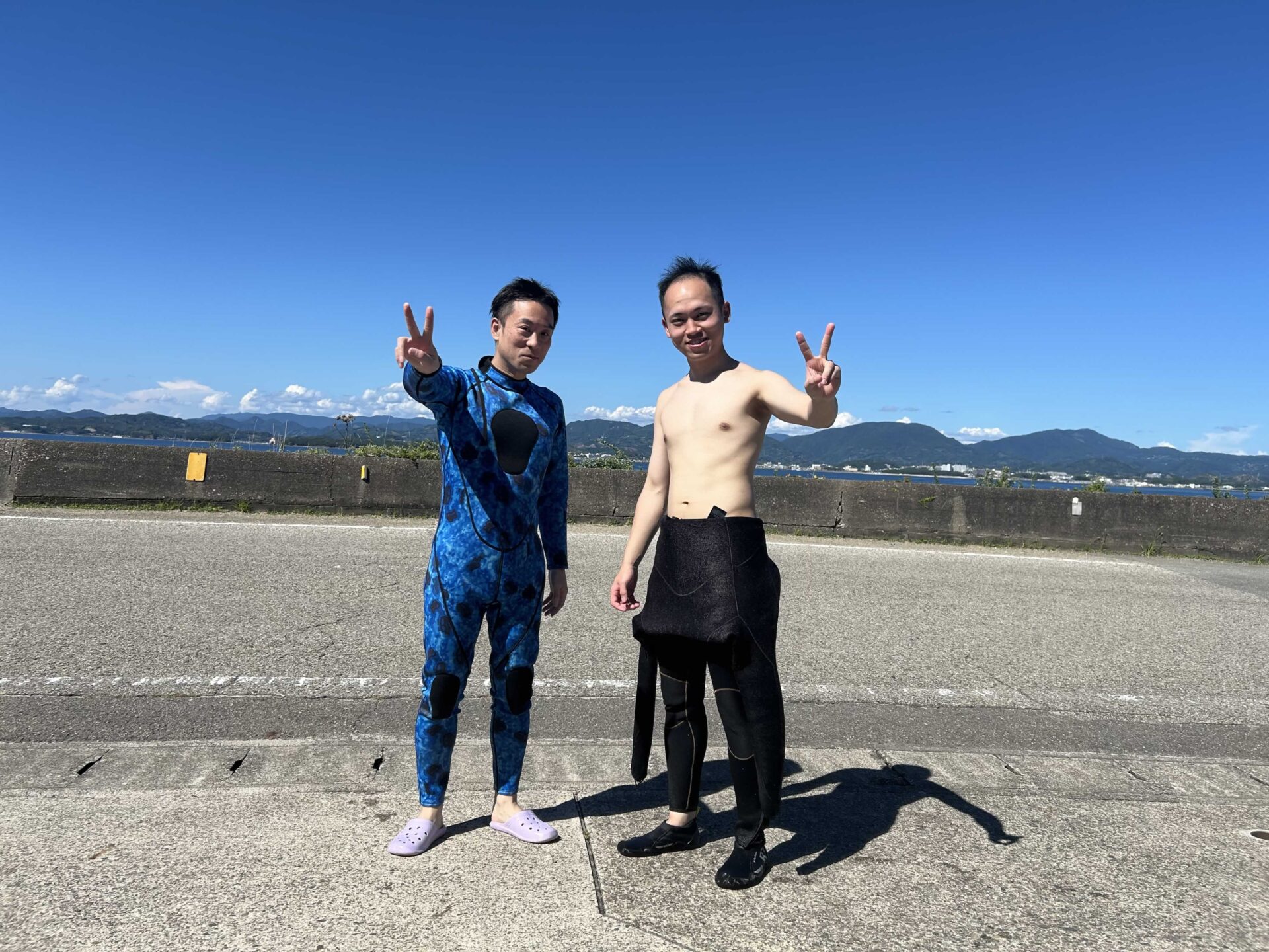 海辺でピースサインをするダイバーたち