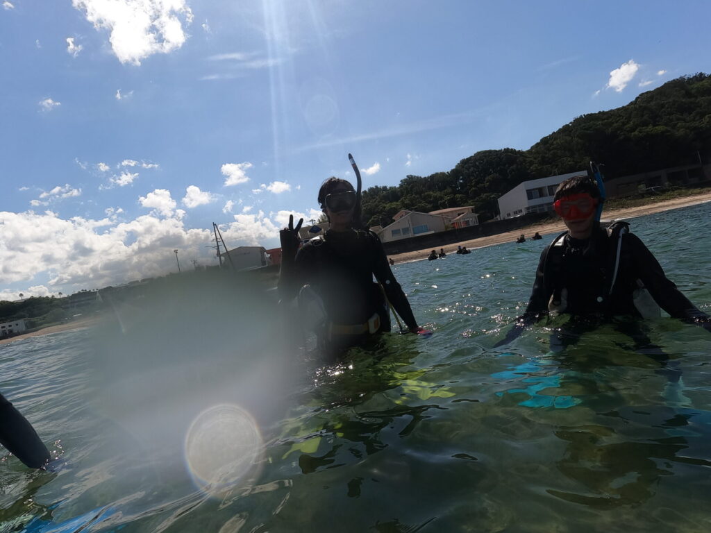 白浜の海でダイビング器材を着け、笑顔でピースサインをする参加者