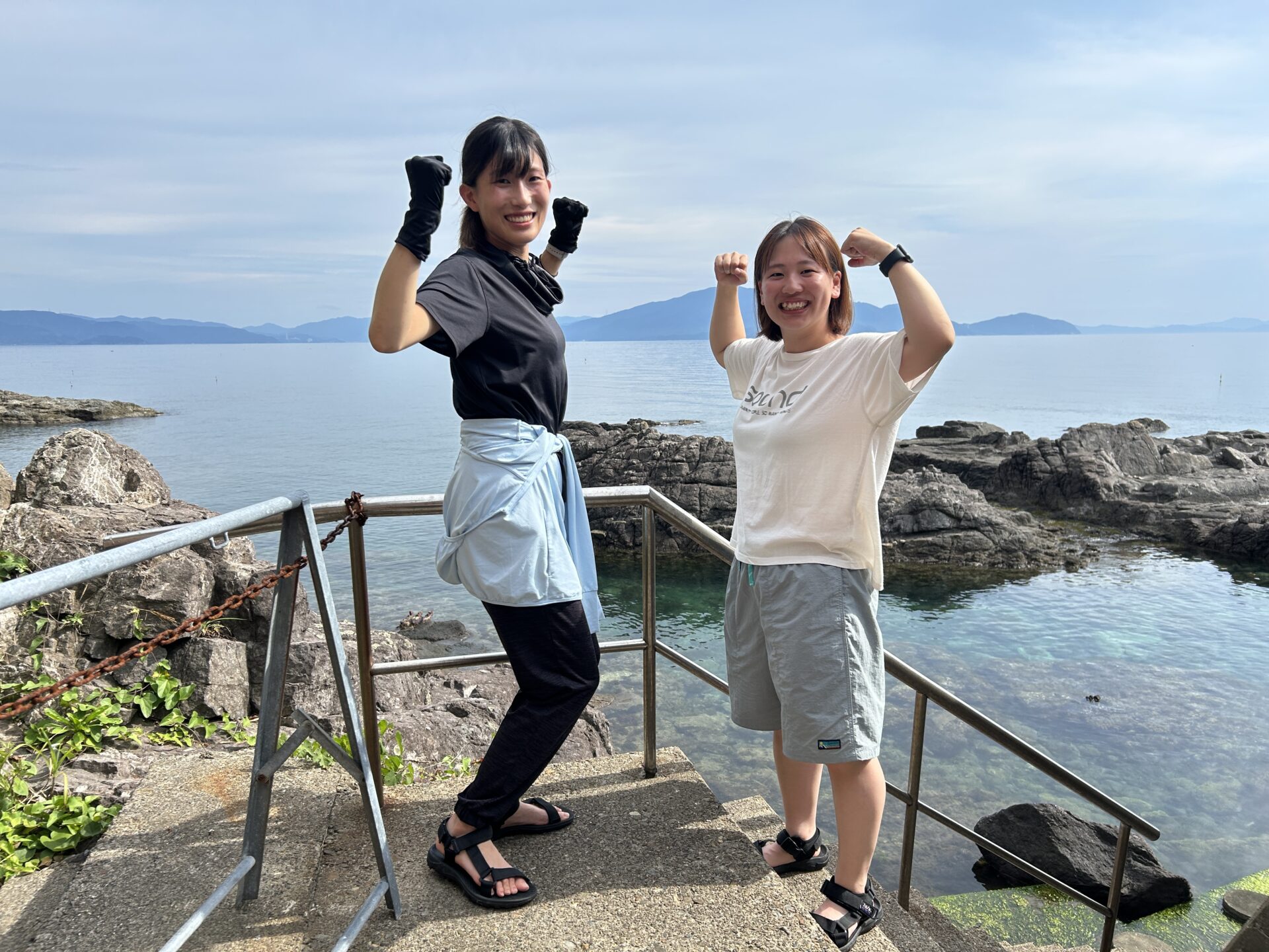南越前の海を背景に笑顔でポーズ