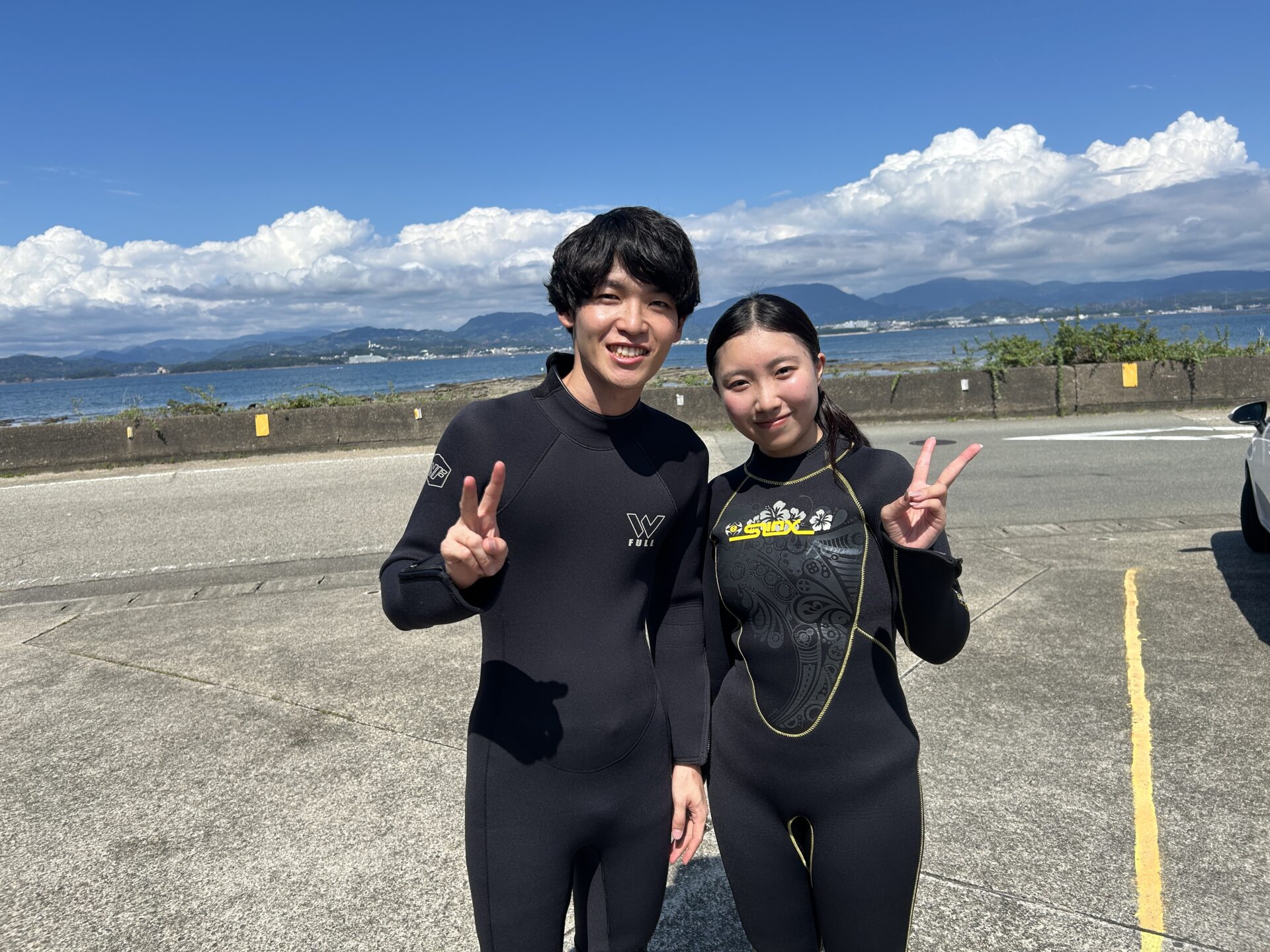 白浜の海を背景にウェットスーツ姿で笑顔のお二人
